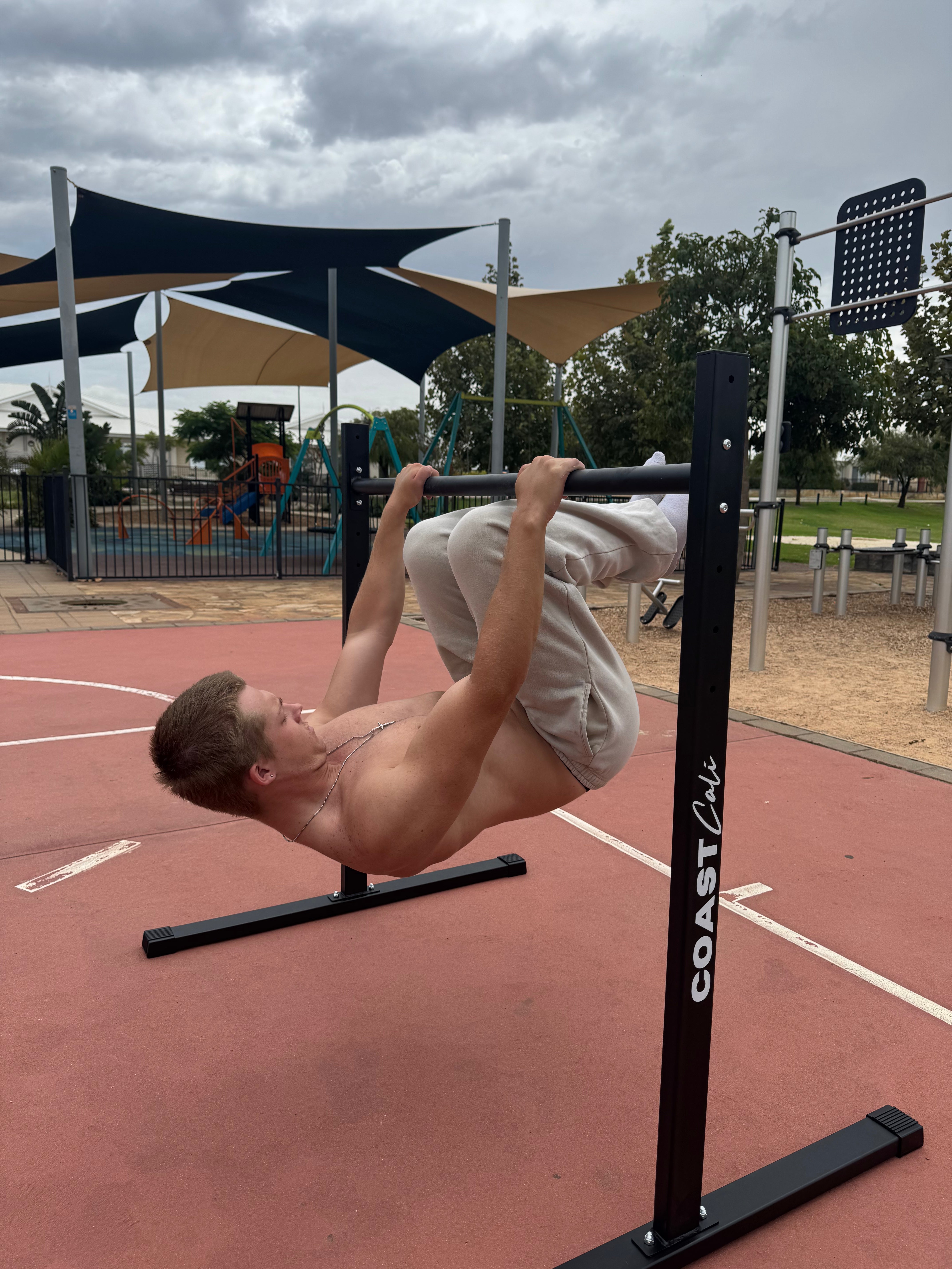 A man doing a tuck lever on a calisthenics static bar.