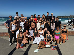 Group of people posing for a photo on a beach with ocean and clear sky in the background