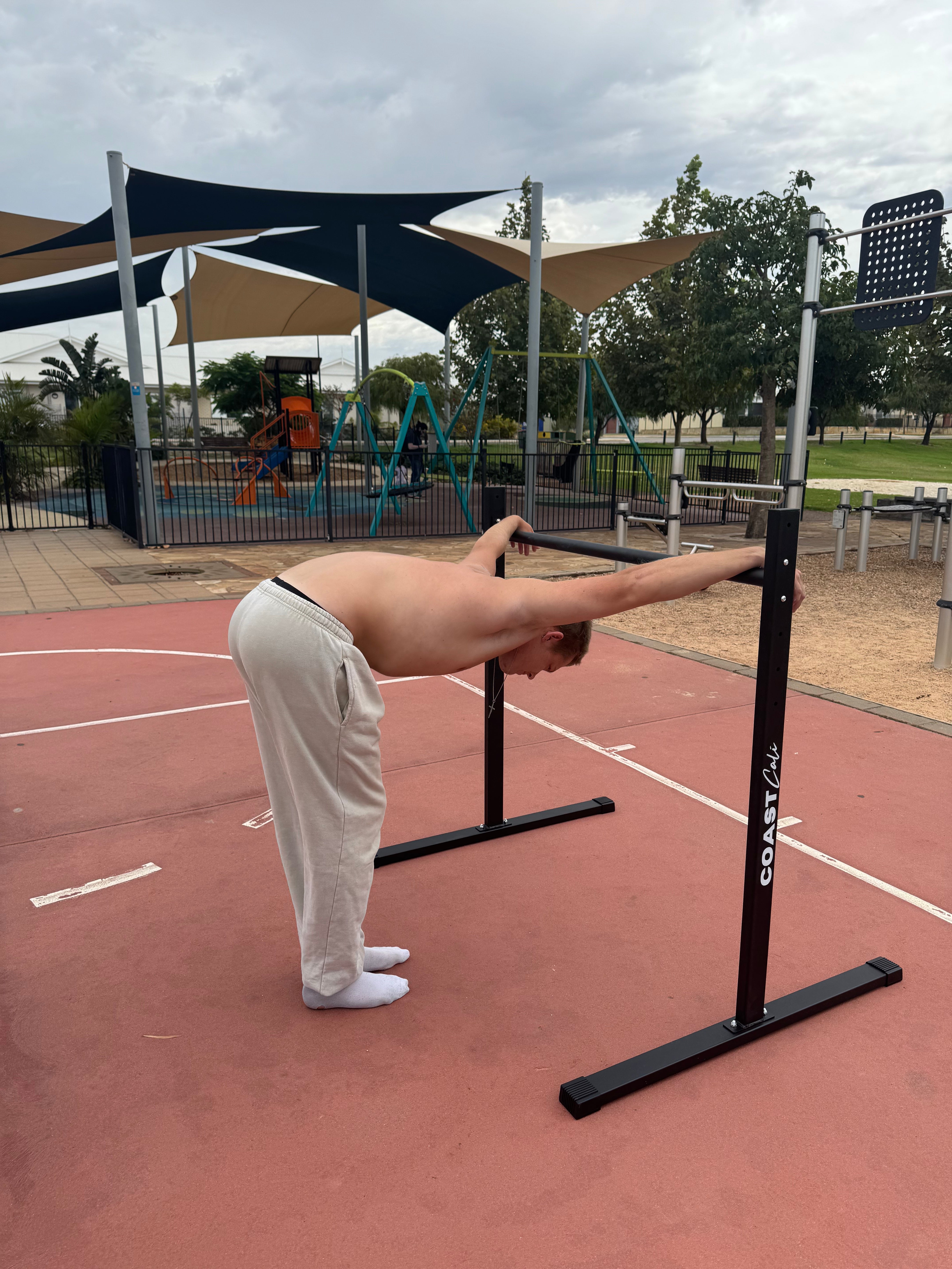 A man stretching on a calisthenics static bar.