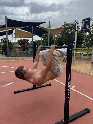 A man doing a tuck lever on a calisthenics static bar.